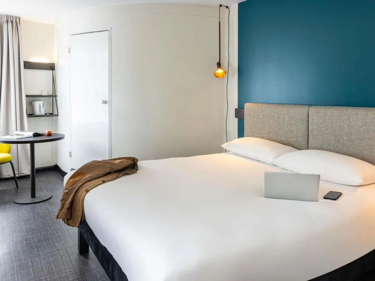 a bedroom with a white bed with a laptop on it at ibis Bristol Temple Meads in Bristol