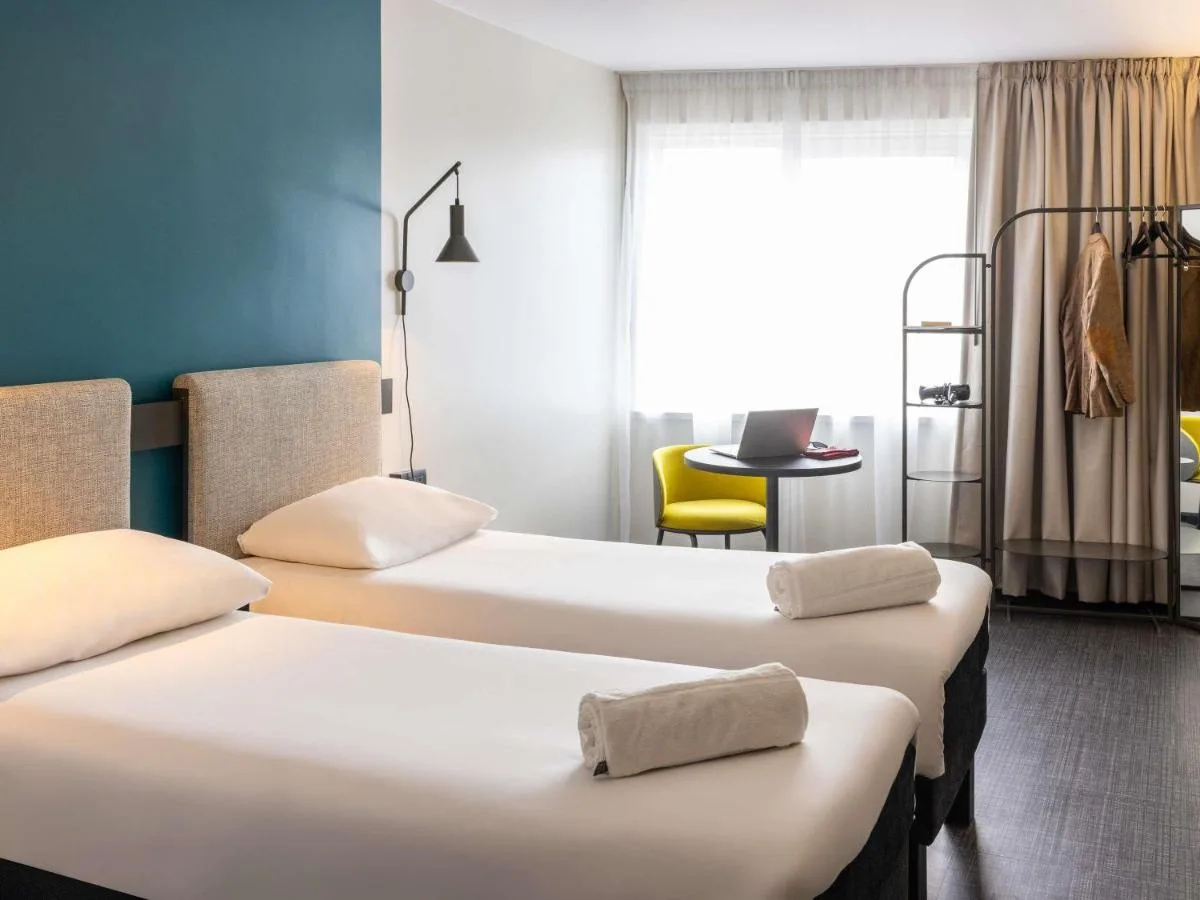 a room with two beds and a table with a laptop at ibis Bristol Temple Meads in Bristol